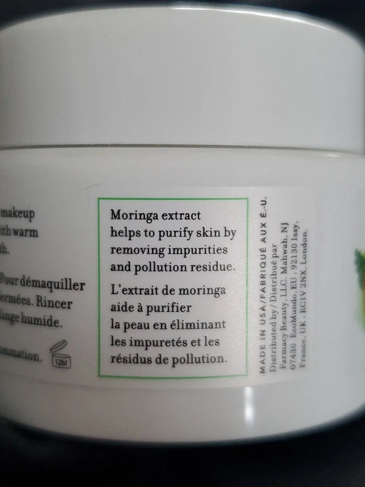 Close-up of a white cosmetic jar showing the back label with text about moringa extract, including English and French copy and a green border around the main text box.