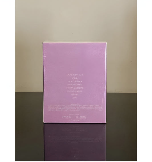 Chanel Hydrosacral Eau de Parfum packaging box in a light lavender purple color, standing upright on a dark reflective surface against a neutral beige background.