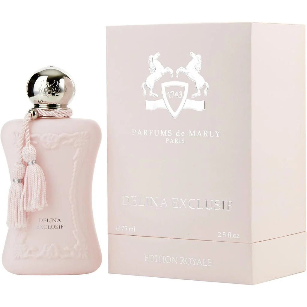A pale blush pink perfume bottle with a silver spherical cap and pink tassel, shown next to its matching pale pink box. The box is branded Parfums de Marly Paris and reads Delina Exclusif Edition Royale.