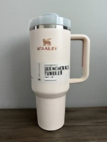 A cream-colored travel tumbler with a handle and lid, featuring the brand name 'ESALFI' and a logo, standing on a dark wooden surface against a gray wall.