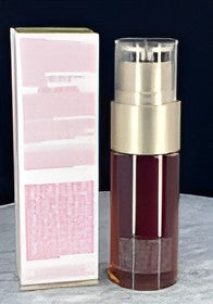 A cosmetic bottle with a gold pump and clear cap stands next to its pink and white box on a light gray surface against a dark background.