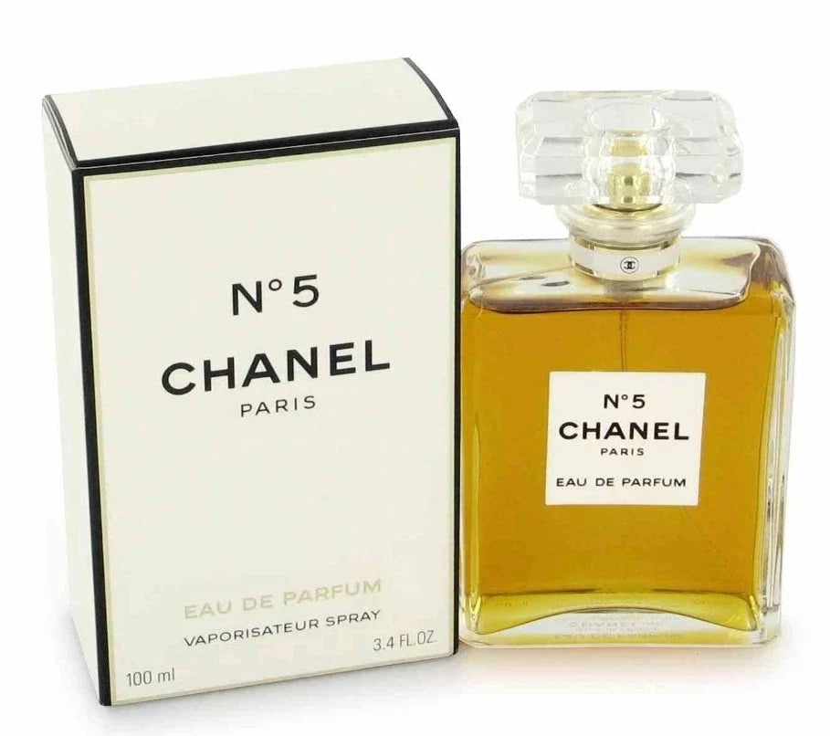 Chanel No. 5 Eau de Parfum shown with its white box and the clear glass perfume bottle filled with amber liquid, on a white background.