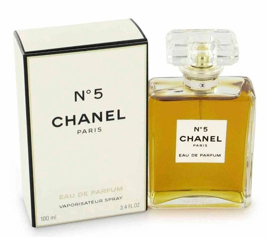 Chanel No. 5 Eau de Parfum shown with its white box and the clear glass perfume bottle filled with amber liquid, on a white background.