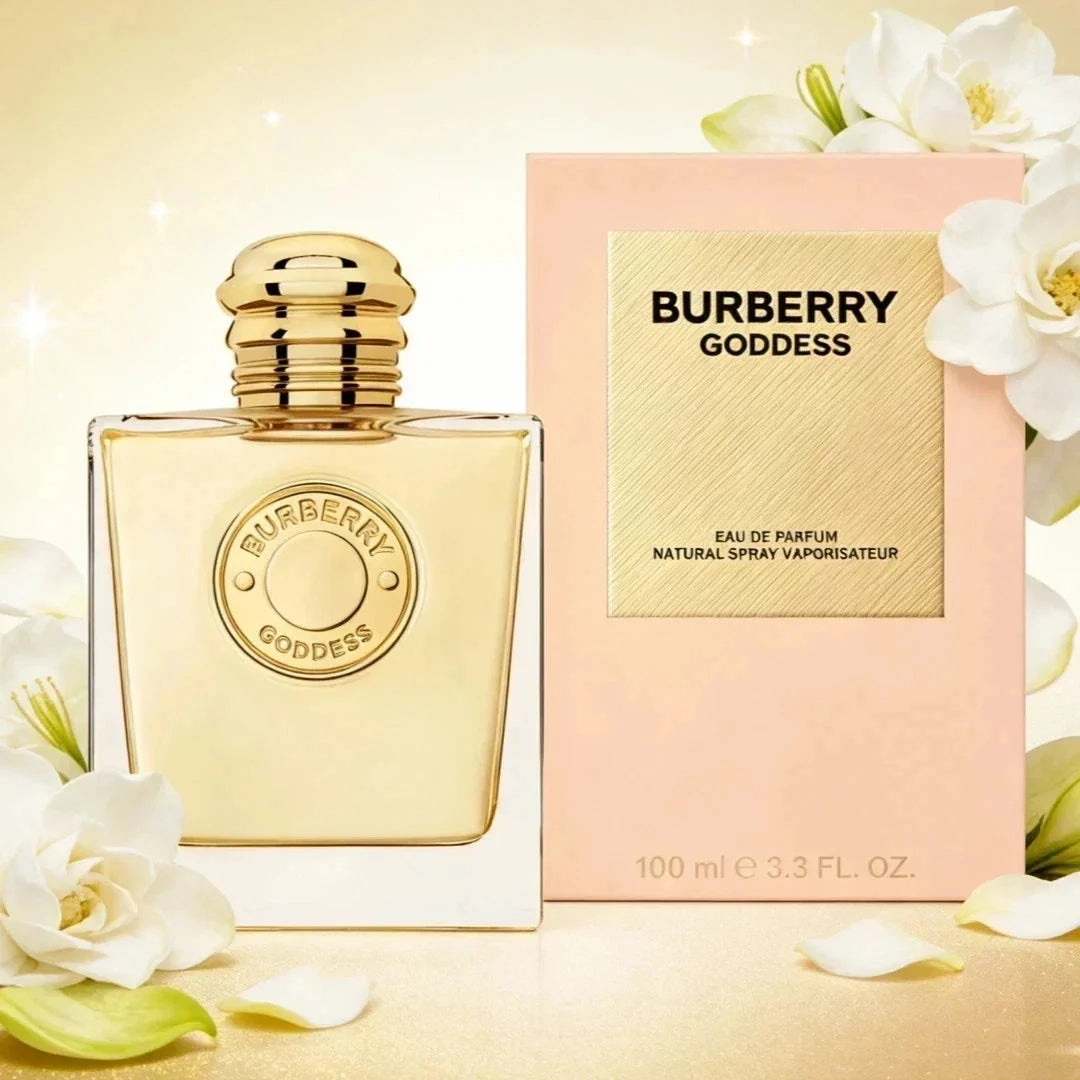 Burberry Goddess Eau de Parfum bottle with a gold cap next to its pink packaging box, decorated with white flowers on a warm beige background.