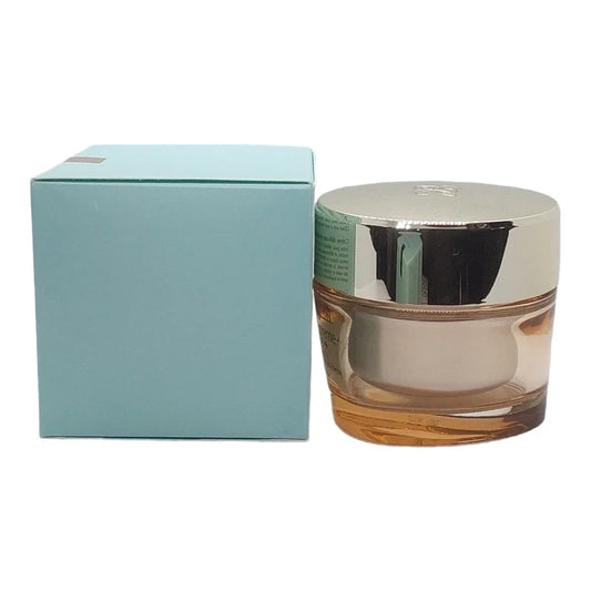 A cosmetic cream jar with a reflective silver lid and amber glass base, shown next to its light blue packaging box on a white background.